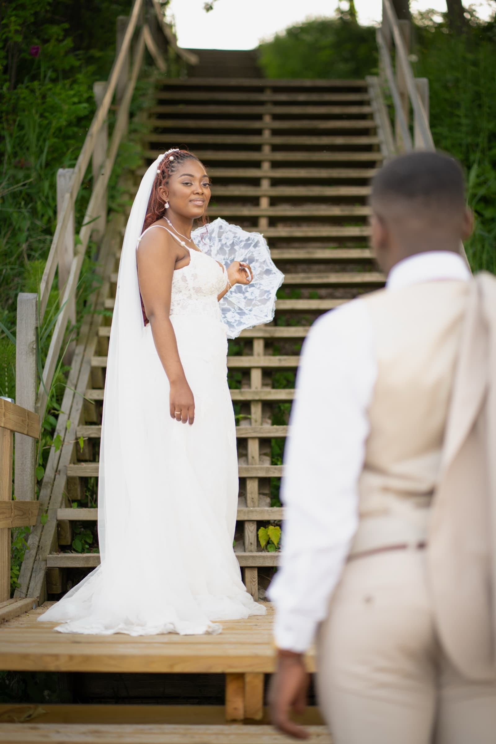 Bride in sharp focus on wooden boardwalk steps, groom softened in the foreground