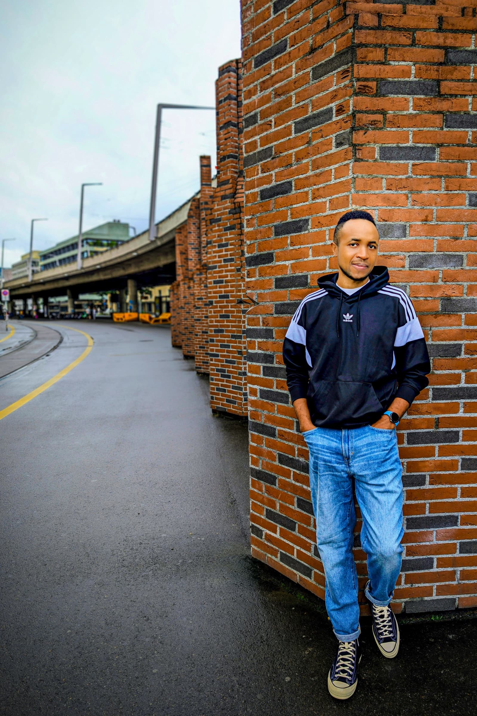 Adidas hoodie, full-length urban portrait by brick wall